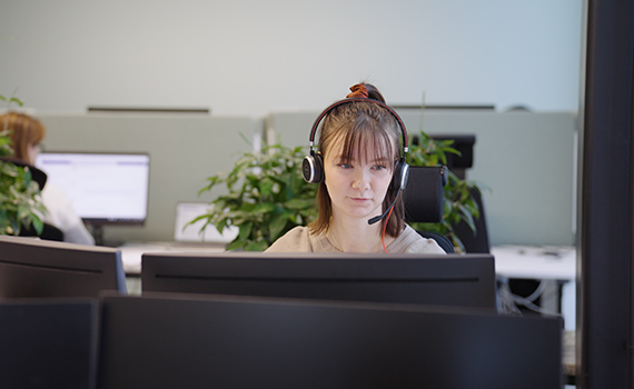 Kundsupportmedarbetare med headset sitter vid ett skrivbord och tar emot samtal